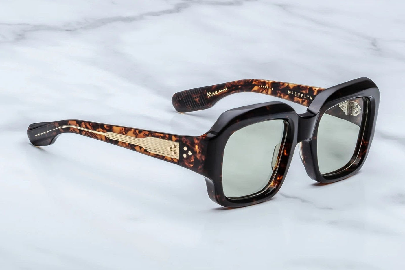 Sunglasses with tortoiseshell frame and gold accents on a light gray background