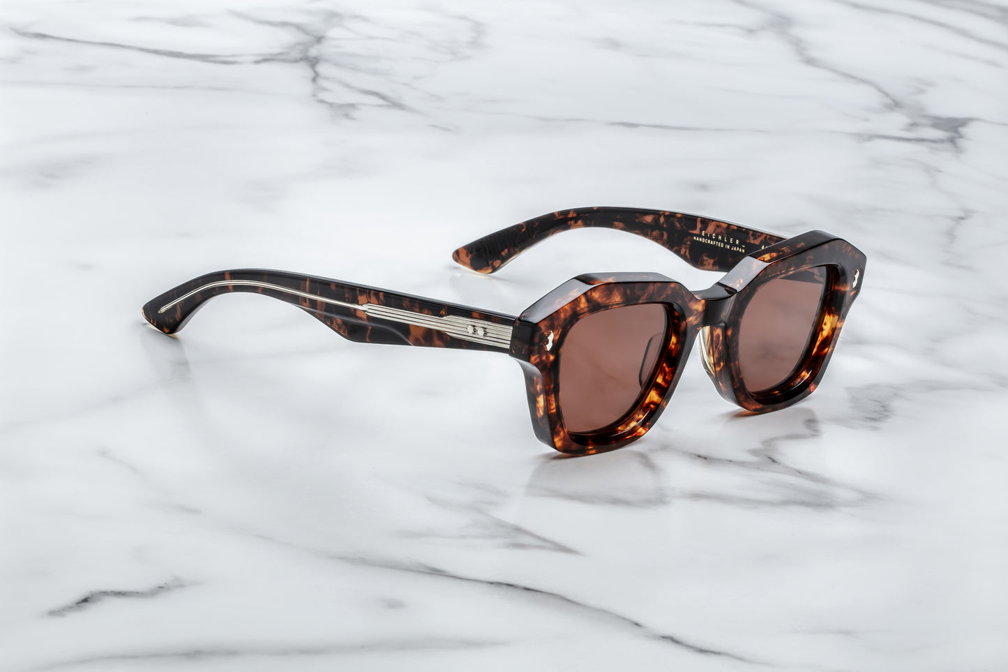 Sunglasses with tortoiseshell frame and brown lenses on a marble surface