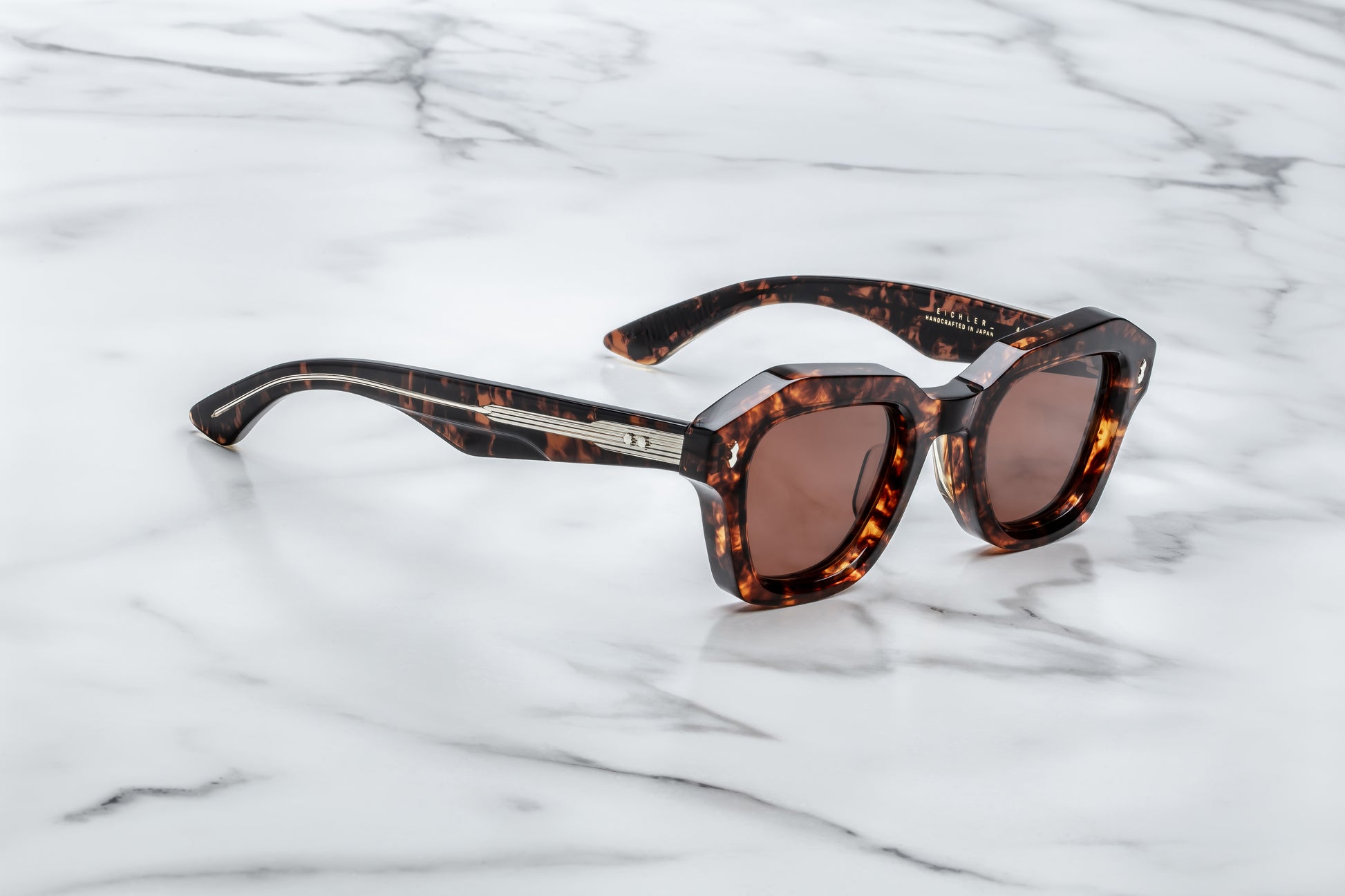 Sunglasses with tortoiseshell frame and brown lenses on a marble surface