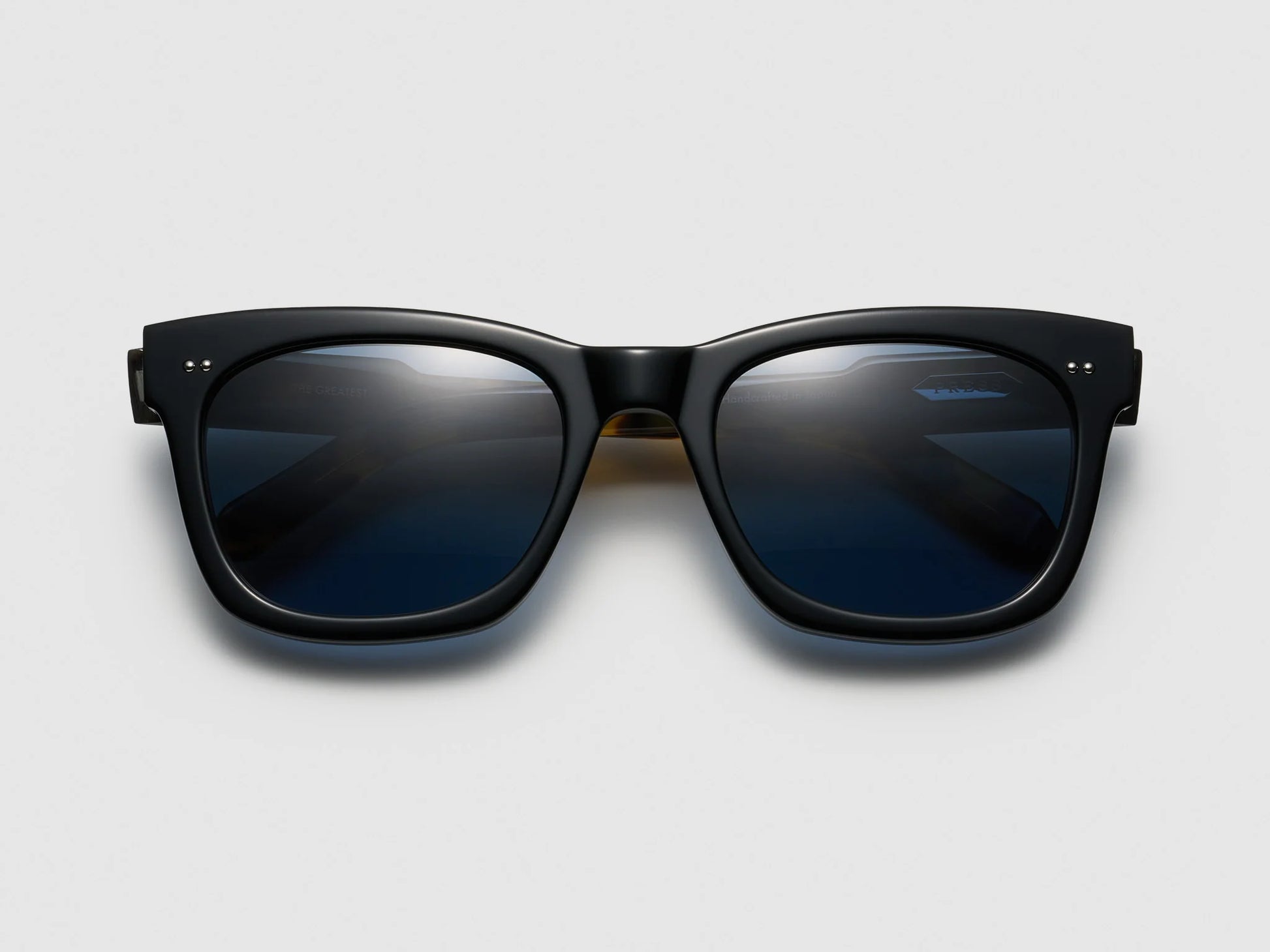 Black sunglasses with dark lenses on a light gray background